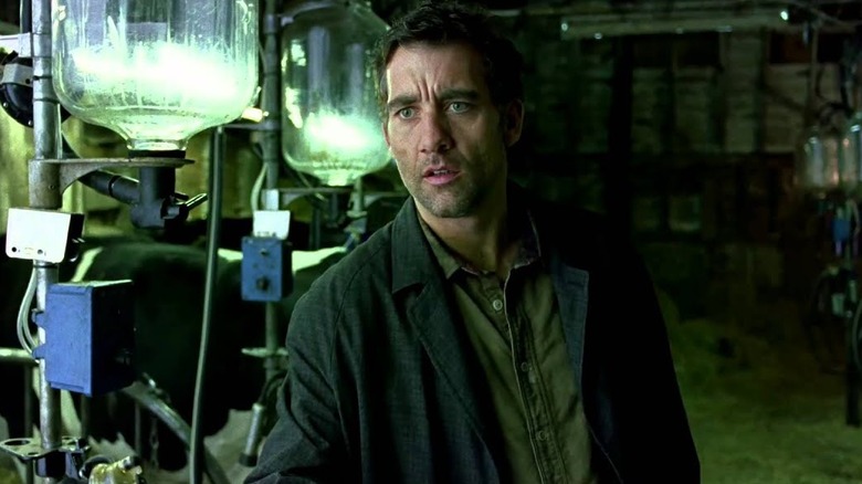 Clive Owen as Theo Faron, walking past canisters in Children of Men.