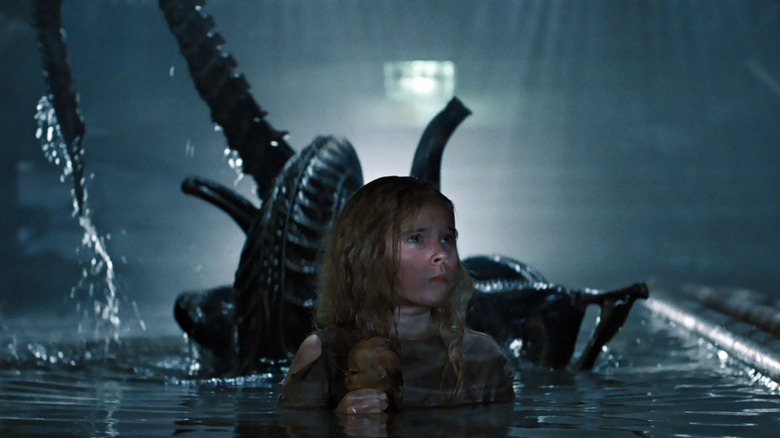 Carrie Henn as Newt with the Xenomorph rising out of the water behind her in Aliens
