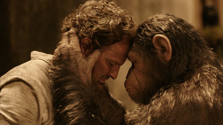 Jason Clarke as Malcolm and Andy Serkis as Caesar, touching foreheads in Dawn of the Planet of the Apes
