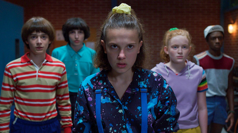 Eleven (Millie Bobby Brown) stands determined, backed by Will (Noah Schnapp), Mike (Finn Wolfhard), Max (Sadie Sink), and Lucas Caleb McLaughlin) in Stranger Things