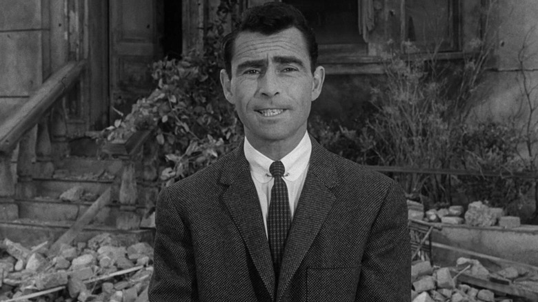 Rod Serling speaks to the camera while standing in front of rubble in The Twilight Zone (1959)