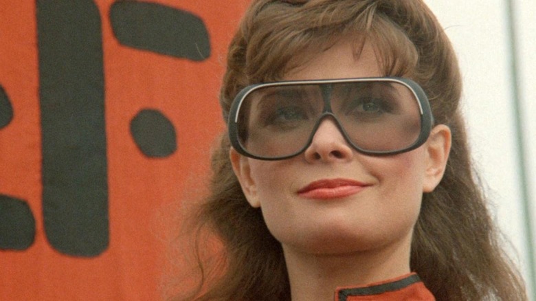 Diana (Jane Badler) smirks as she wins over humanity's hearts for trinkets on V.