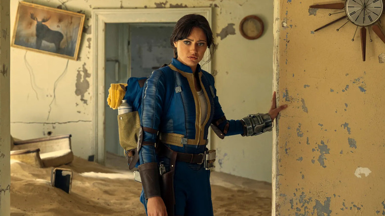 Ella Purnell as Lucy MacLean, walking through an abandoned home in Fallout.