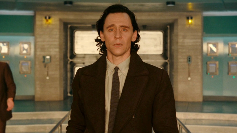 Tom Hiddleston as Loki, staring through a window stunned in Loki.