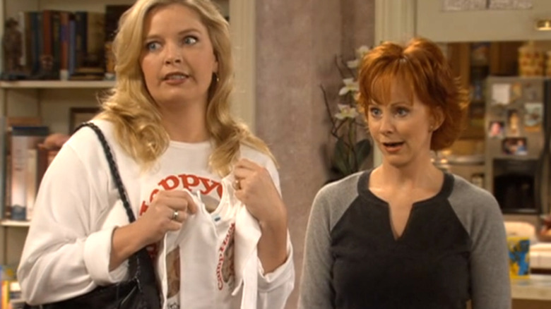 Melissa Peterman as Barbara Jean and Reba McEntire as Reba stand in Reba's living room on Reba