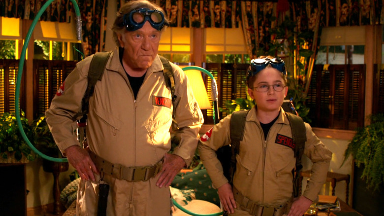 George Segal as Pops and Sean Giambrone as Adam Goldberg stand together in Ghostbusters uniforms in The Goldbergs