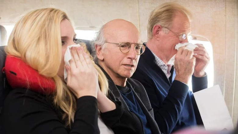 Larry David as a fictional version of himself looking uncomfortable on a plane in Curb Your Enthusiasm