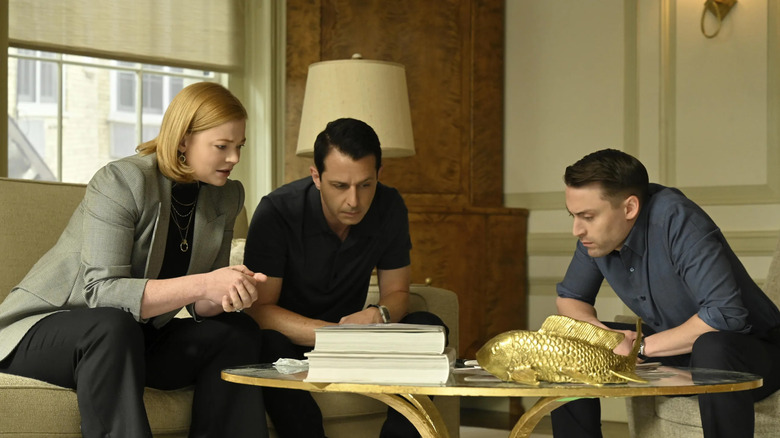 The Roy children surround a phone in Succession.