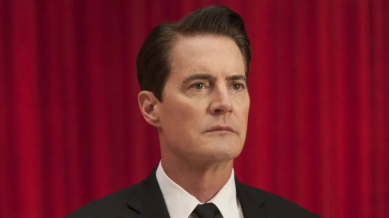 Kyle MacLachlan as Special Agent Dale Cooper, standing in front of the red curtain in Twin Peaks.