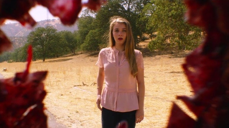 Alexa Yeames as Sara, looking through a bullet hole in Downrange