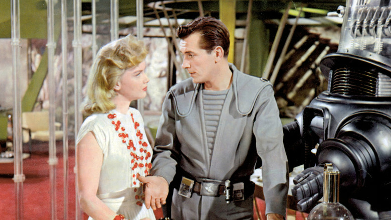 Anne Francis as Altaira "Alta" Morbius talking to Jack Kelly as Lieutenant Jerry Farman next to Robby the Robot in the Morbius house in Forbidden Planet
