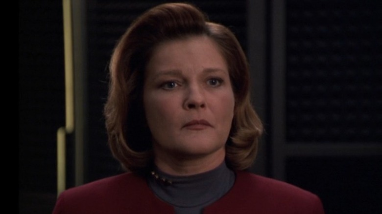 Kathryn Janeway (Kate Mulgrew) stands stoically in Star Trek: Voyager