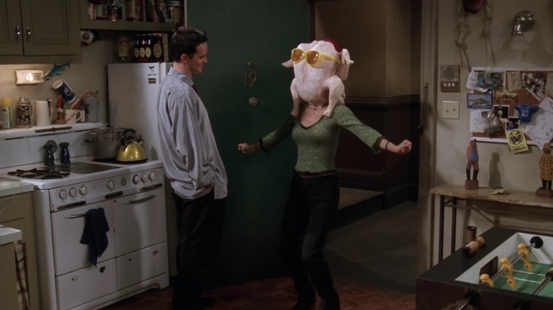 Matthew Perry as Chandler Bing laughing at Courteney Cox as Monica Geller dancing with a turkey on her head on Friends