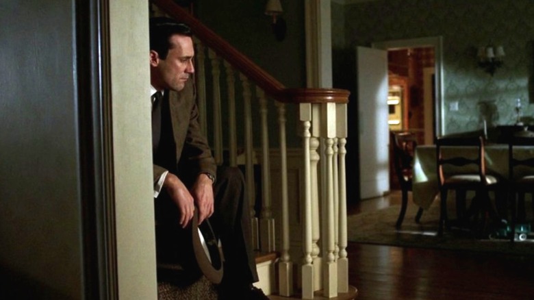 Jon Hamm as Don Draper sitting alone on the stairs of his house on Mad Men