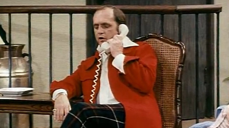 Bob Newhart as Dr. Robert Hartley sitting on a chair and talking on the phone on The Bob Newhart Show