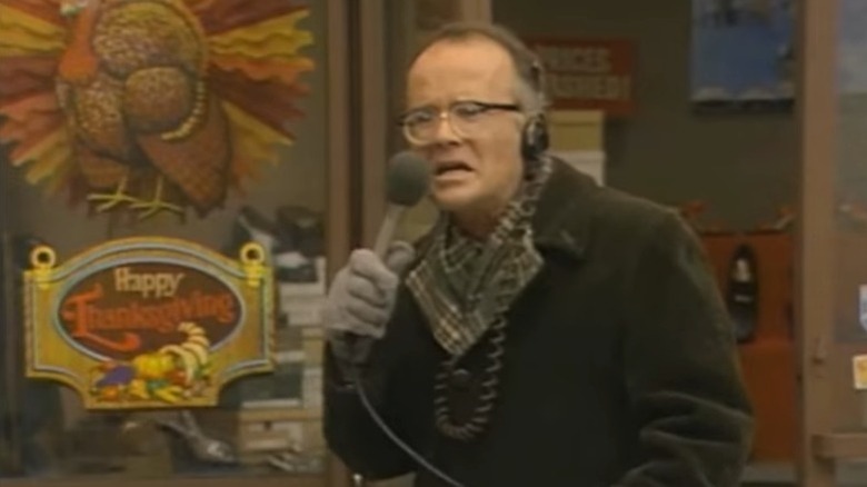 Richard Sanders as Les Nessman making a horrified expression while standing on the street and speaking into a microphone on WKRP in Cincinnati