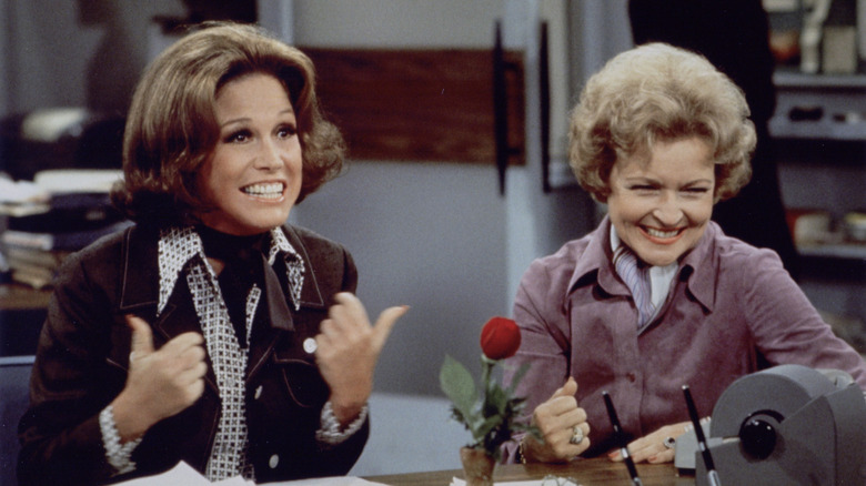 Mary Tyler Moore as Mary smiling in an office next to Betty White laughing as Sue on The Mary Tyler Moore Show