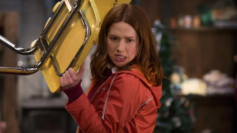Ellie Kemper as Kimmy Schmidt holding a chair above her head in Unbreakable Kimmy Schmidt
