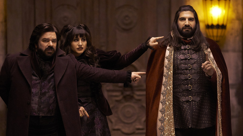 Matt Berry as Laszlo and Natasie Demetriou as Nadja pointing at Kayvan Novak as Nandor in What We Do in the Shadows