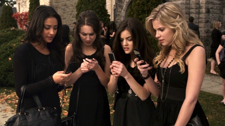 Shay Mitchell as Emily Fields, Troian Bellisario as Spencer Hastings, Lucy Hale as Aria Montgomery, and Ashley Benson as Hanna Marin all looking at their phones on Pretty Little Liars