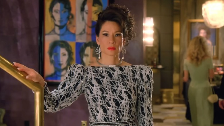 Lucy Liu as Simone Grove standing by a staircase with a worried expression on Why Women Kill