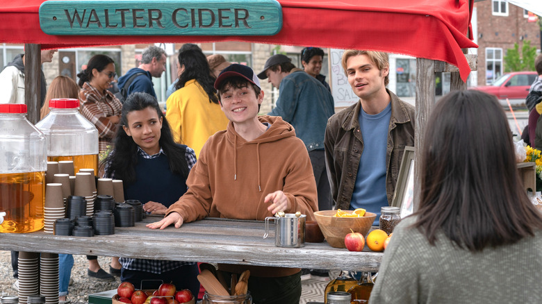 Nikki Rodriguez as Jackie Howard stands at an apple cider stand with Ashby Gentry as Alex and Noah LaLonde as Cole in My Life with the Walter Boys