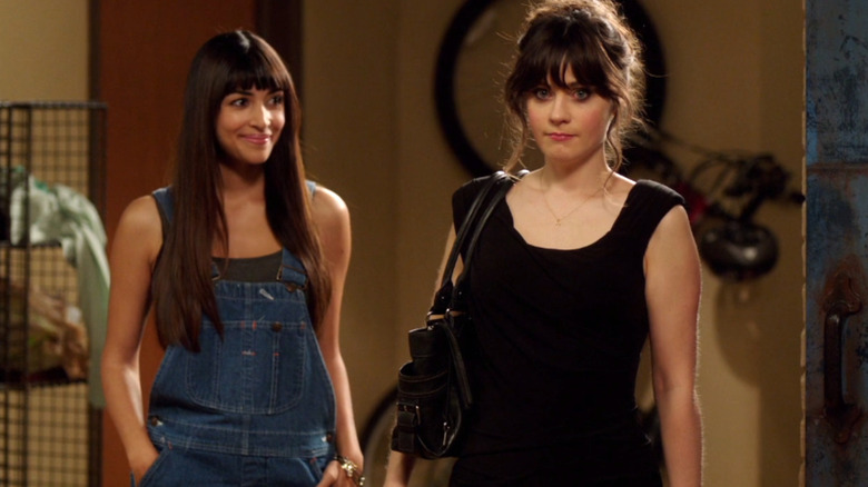 Hannah Simone as Cece Parikh stands next to Zooey Deschanel as Jess Day in her apartment in New Girl