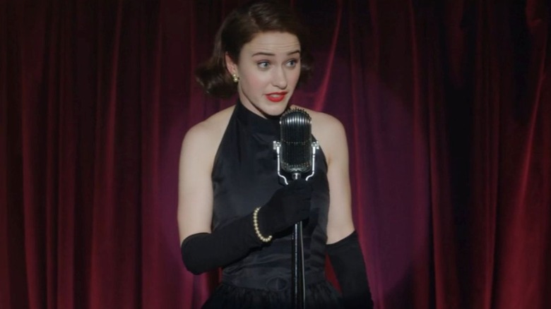Rachel Brosnahan as Midge Maisel stands in front of a mic on The Marvelous Mrs. Maisel