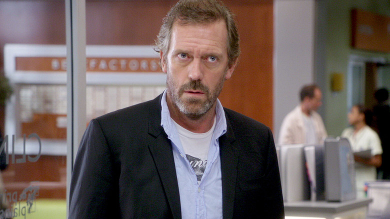 Hugh Laurie as Dr. House standing in his office on House