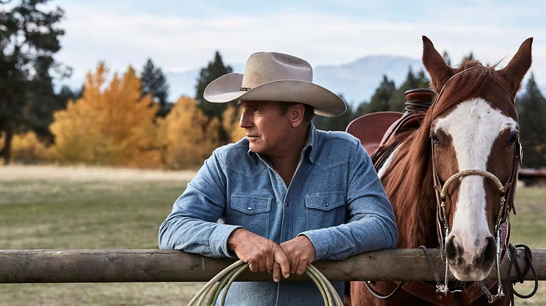 Kevin Costner as John Dutton, standing with a horse on Yellowstone