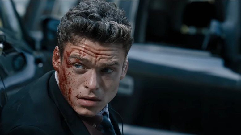Richard Madden as David Budd kneeling in front of car with blood on his face in Bodyguard