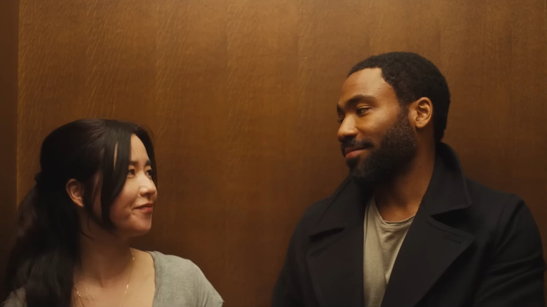 Maya Erskine as Jane and Donald Glover as John smiling at each other in a wood-paneled elevator in Mr. & Mrs. Smith