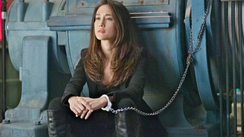 Maggie Q as Nikita sitting handcuffed to blue machinery in Nikita
