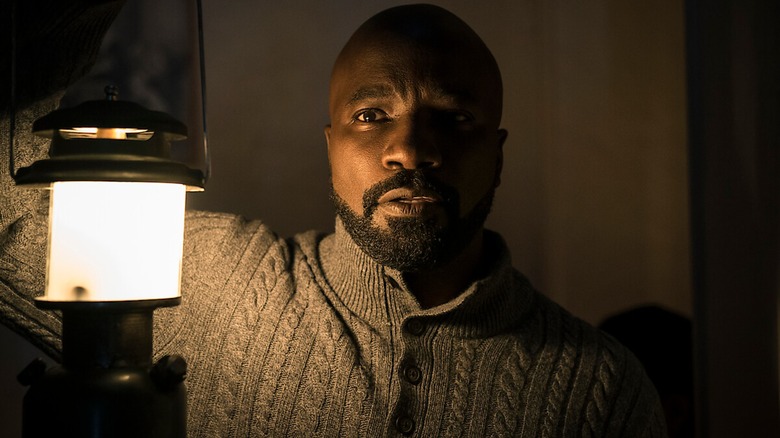 Mike Coulter, as Father Acosta, holds an old lantern and wears a very cozy sweater in Evil