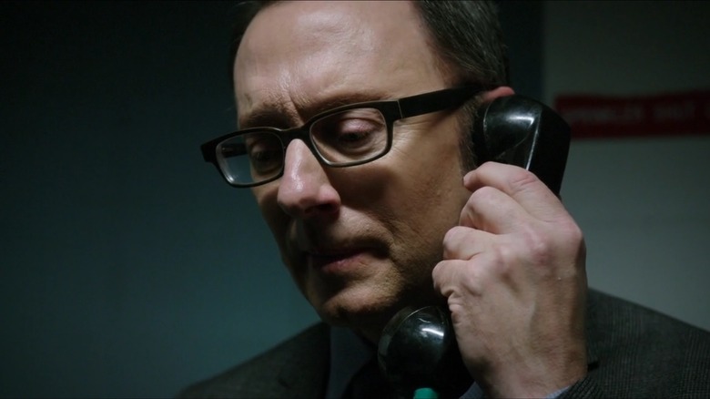 Michael Emerson, as the reclusive Finch, pensively answers the phone in Person of Interest