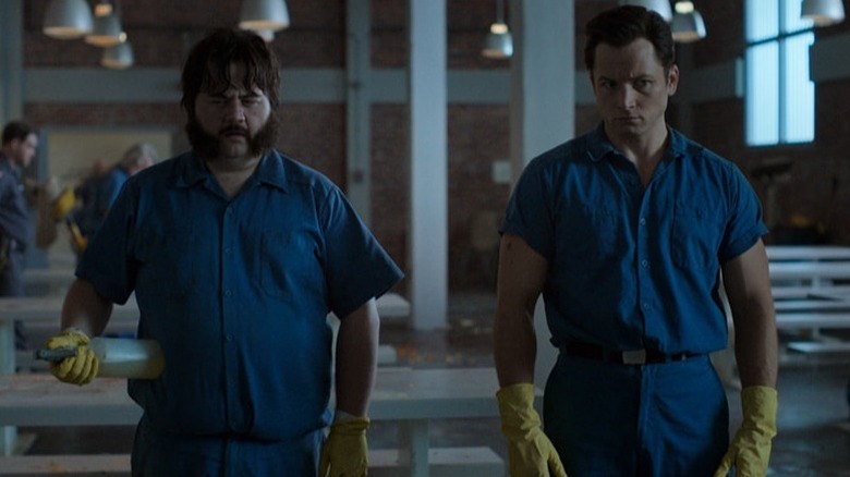 Larry Hall (Paul Walter Hauser) and Jimmy Keene (Taron Egerton) stand in a cafeteria wearing cleaning gloves in Black Bird