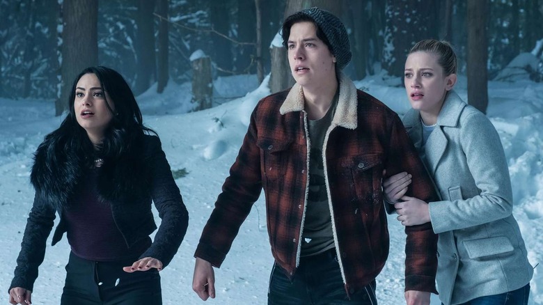 Veronica Lodge (Camila Mendes), Jughead Jones (Cole Sprouse), and Betty Cooper (Lili Reinhart) stand shocked in the snow in Riverdale