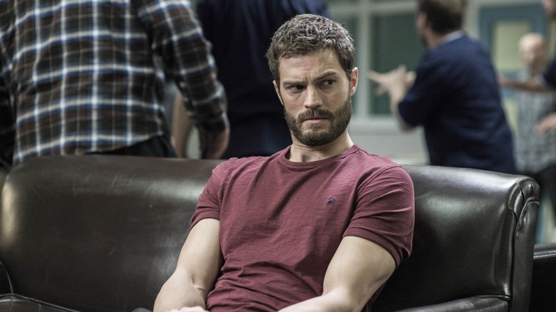 Paul Spector (Jamie Dornan) sits tensely on a leather couch in The Fall