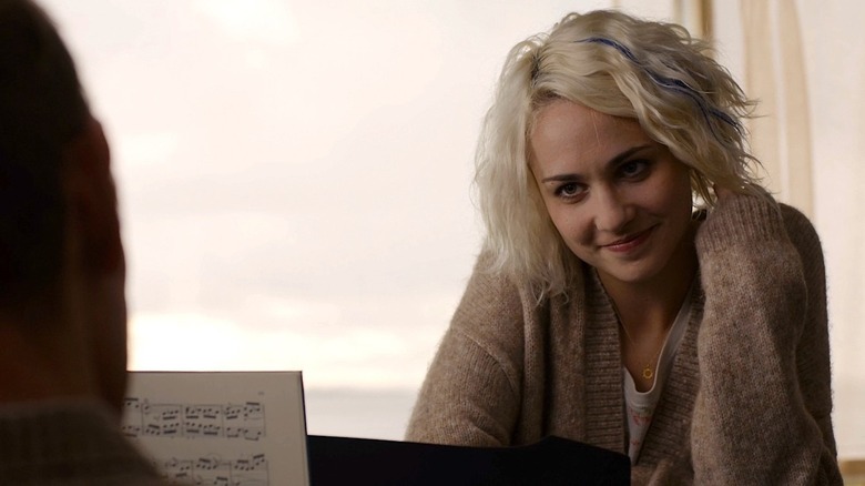 Tuppence Middleton as Riley leaning over a piano and smiling in Sense8