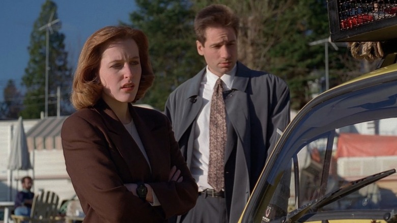 Mulder (David Duchovney) and Scully (Gillian Anderson) looking at a car on The X-Files