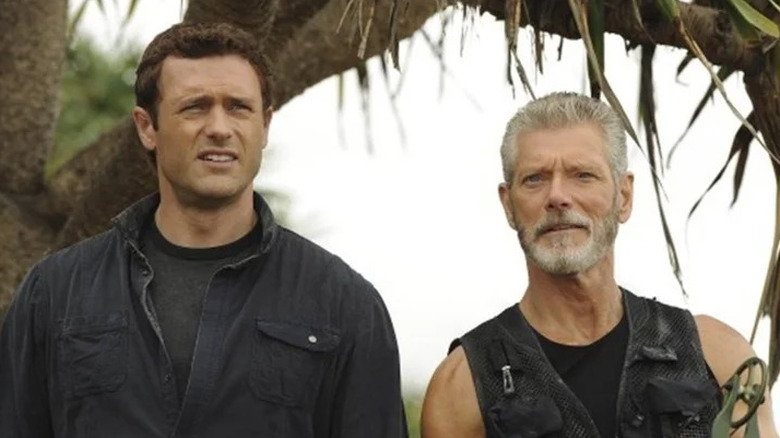 Jim Shannon (Jason O'Mara) and Nathaniel Taylor (Stephen Lang) stand together under a tropical tree in Terra Nova