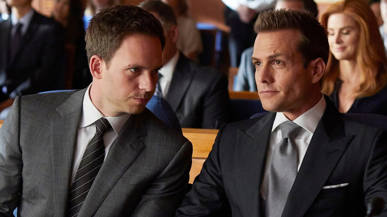 Patrick J. Adams and Gabriel Macht as Mike Ross and Harvey Specter sitting together in court on Suits