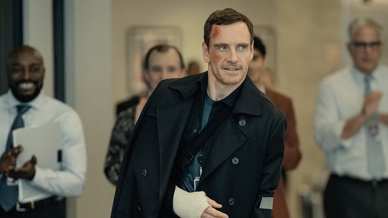 Brandon Colby (Michael Fassbender) smiles as an office claps for him in The Agency
