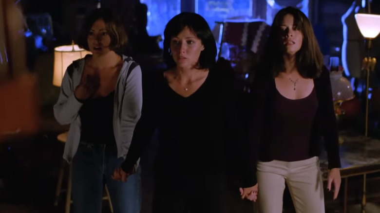 Alyssa Milano's Phoebe, Shannen Doherty's Prue, and Holly Marie Combs' Piper holding hands in Charmed