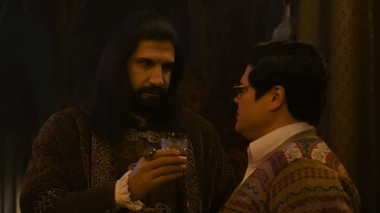 Kayvan Novak's Nandor giving a glass to Harvey Guillén's Guillermo
