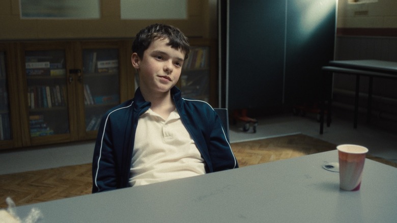 Owen Cooper as Jamie Miller sitting and smiling in Adolescence