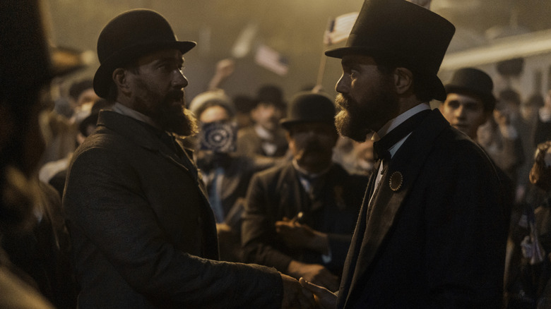 Matthew Macfadyen as Charles Guiteau shaking hands with Michael Shannon as James Garfield in the middle of a crowd in Death by Lightning