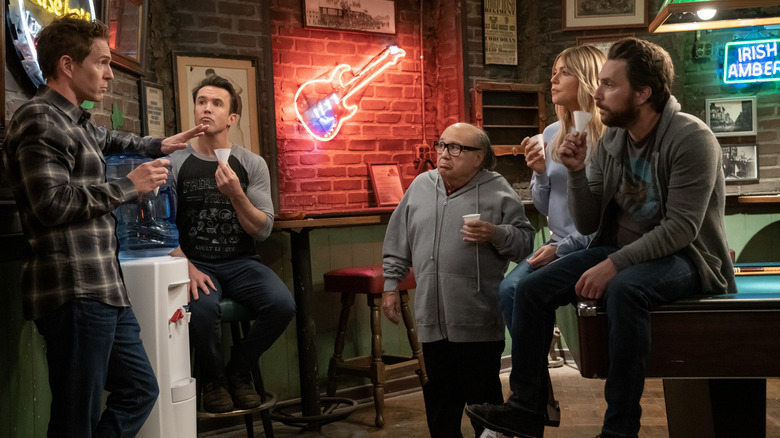 Glenn Howerton as Dennis, Rob Mac as Mac, Danny DeVito as Frank, Kaitlin Olson as Dee, and Charlie Day as Charlie sitting around the water cooler on It's Always Sunny in Philadelphia season 17