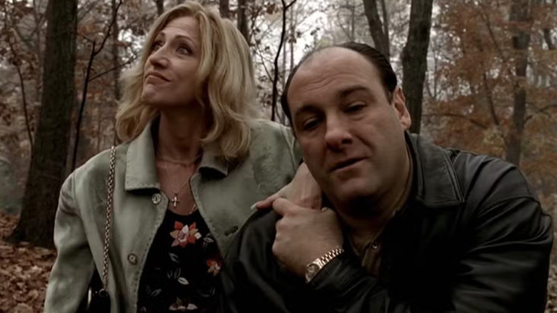 Edie Falco and James Gandolfini as Carmela and Tony Sopranos, sitting together in the woods in The Sopranos.