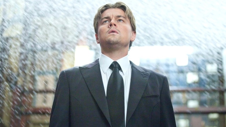 Cobb (Leonardo DiCaprio) stands looking up amid cascading water in Inception